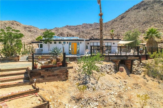 rear view of house with a deck with mountain view and fence