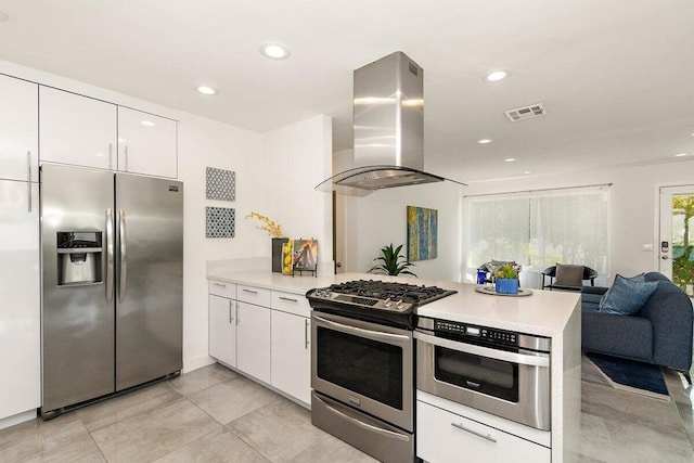 kitchen featuring kitchen peninsula, white cabinets, island range hood, and appliances with stainless steel finishes