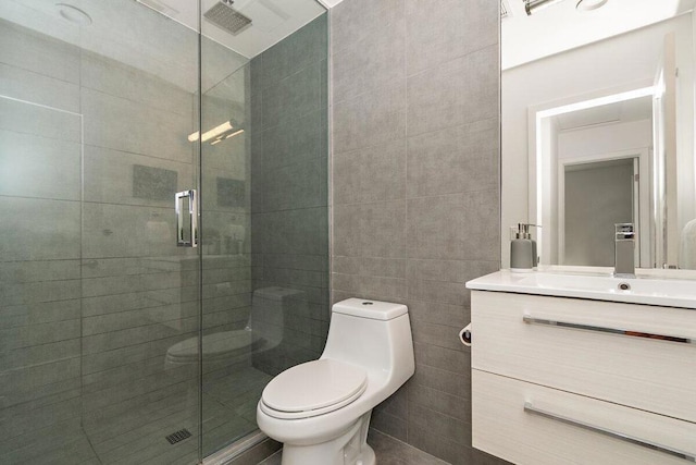 bathroom with tile walls, toilet, a shower with door, and vanity