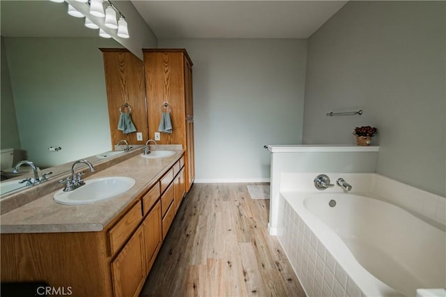 bathroom featuring hardwood / wood-style floors, vanity, toilet, and tiled tub