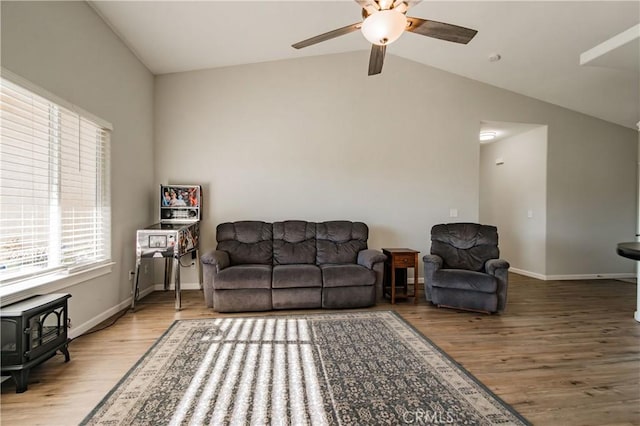 living room featuring hardwood / wood-style flooring, ceiling fan, lofted ceiling, and a wood stove