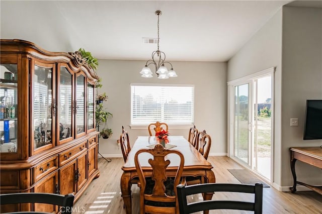 dining area with light wood-type flooring, an inviting chandelier, and lofted ceiling