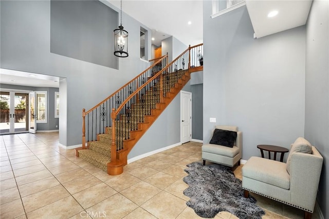 interior space featuring a towering ceiling, french doors, a chandelier, and tile patterned flooring