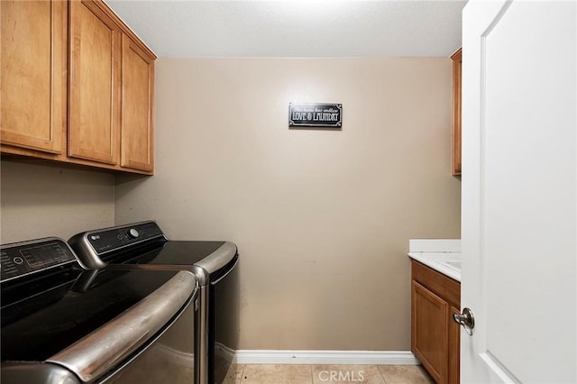 washroom with light tile patterned floors, washing machine and clothes dryer, and cabinets