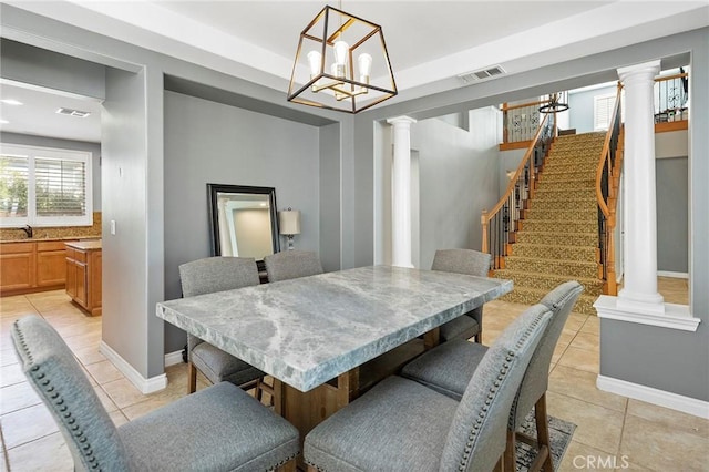 dining space with decorative columns, sink, and light tile patterned floors