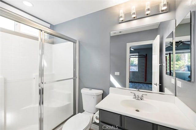 bathroom featuring vanity, toilet, walk in shower, and ceiling fan