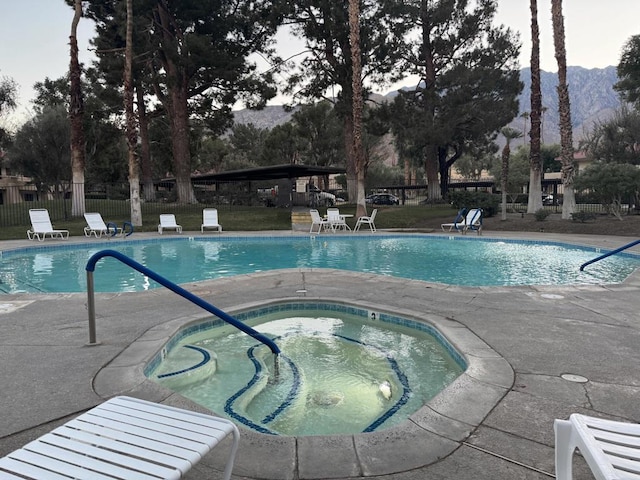 view of pool with a mountain view, a community hot tub, and a patio