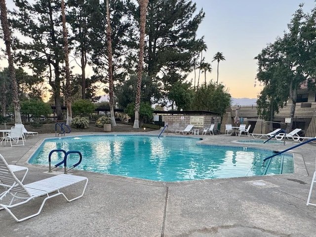 pool at dusk featuring a patio