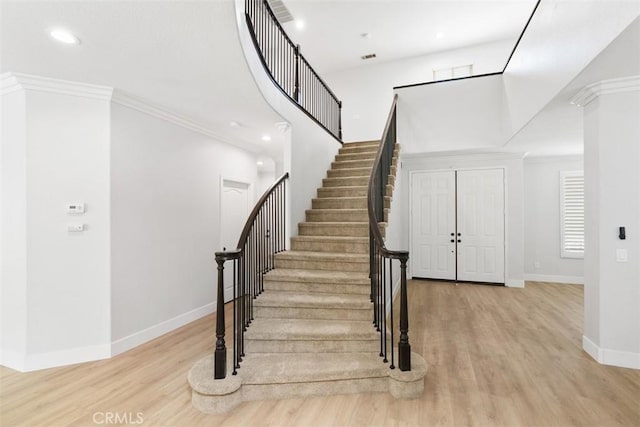 stairs with ornamental molding and hardwood / wood-style flooring