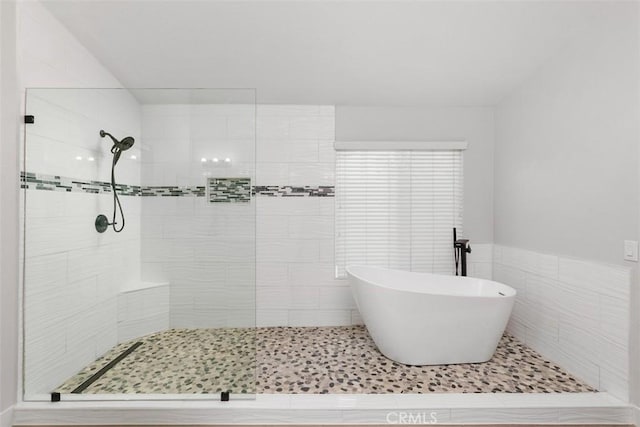 bathroom featuring tile walls and independent shower and bath