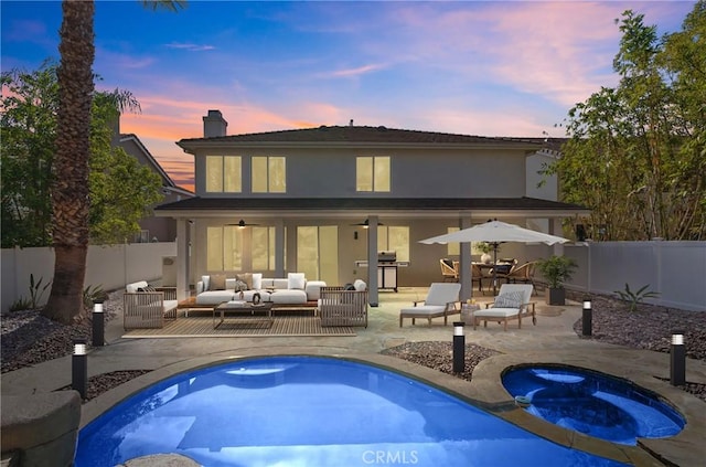 back house at dusk with a pool with hot tub, an outdoor living space, and a patio