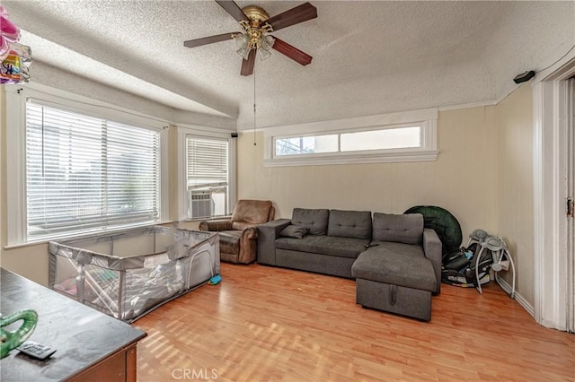 living room featuring cooling unit, vaulted ceiling, light hardwood / wood-style flooring, ceiling fan, and a textured ceiling