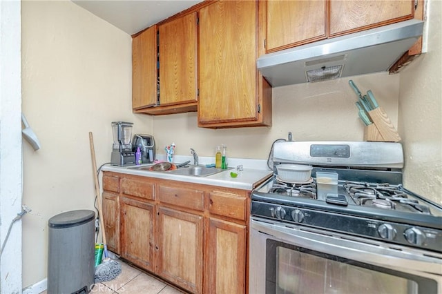 kitchen featuring stainless steel gas range oven, sink, and light tile patterned flooring