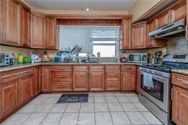 kitchen with light tile patterned flooring, sink, light stone countertops, and stainless steel appliances