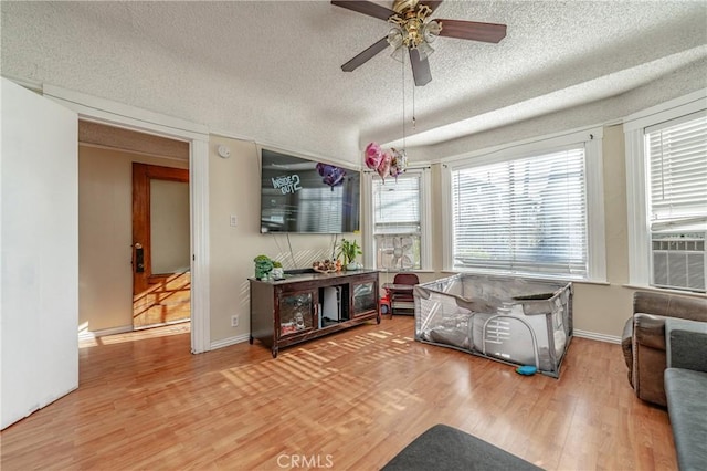 living room featuring ceiling fan, a textured ceiling, and hardwood / wood-style flooring