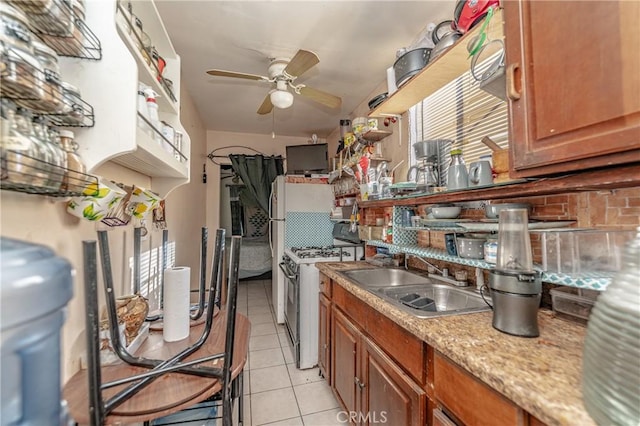 kitchen featuring sink, stainless steel gas stove, ceiling fan, light tile patterned floors, and tasteful backsplash