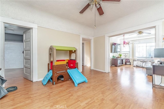 game room with a textured ceiling and light wood-type flooring