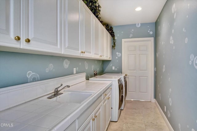 washroom with cabinets, washing machine and dryer, and sink