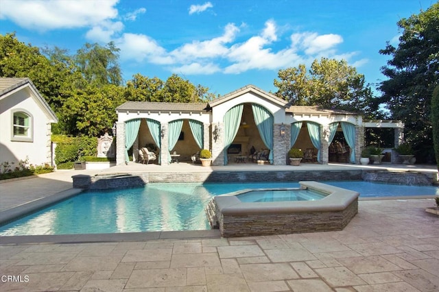 view of swimming pool with an in ground hot tub, an outbuilding, and a patio area