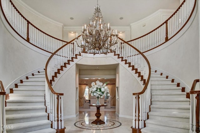 entrance foyer with crown molding, a chandelier, and a high ceiling