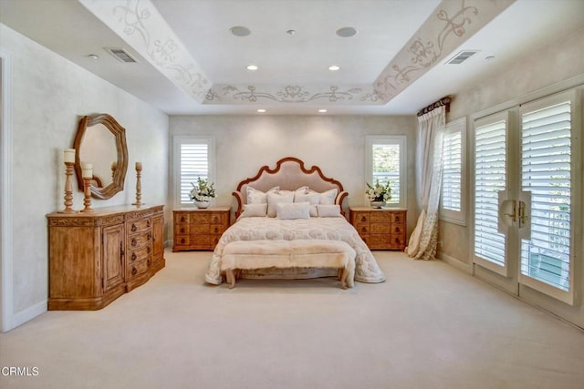 carpeted bedroom with access to exterior and a tray ceiling