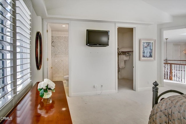 bedroom with connected bathroom, light carpet, and lofted ceiling