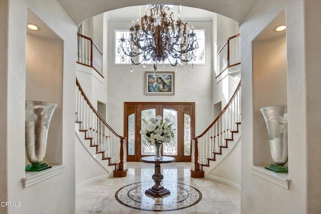 foyer with a towering ceiling, a wealth of natural light, and a chandelier