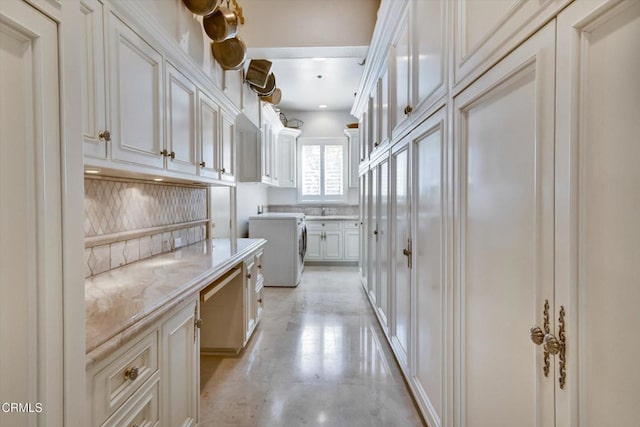 kitchen with backsplash, light stone countertops, and white cabinets