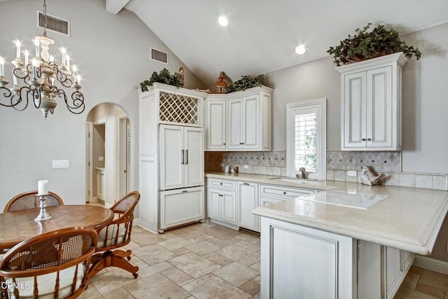 kitchen with backsplash, kitchen peninsula, white cabinets, and decorative light fixtures