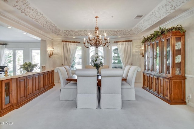 carpeted dining room with a tray ceiling, crown molding, a wealth of natural light, and a chandelier