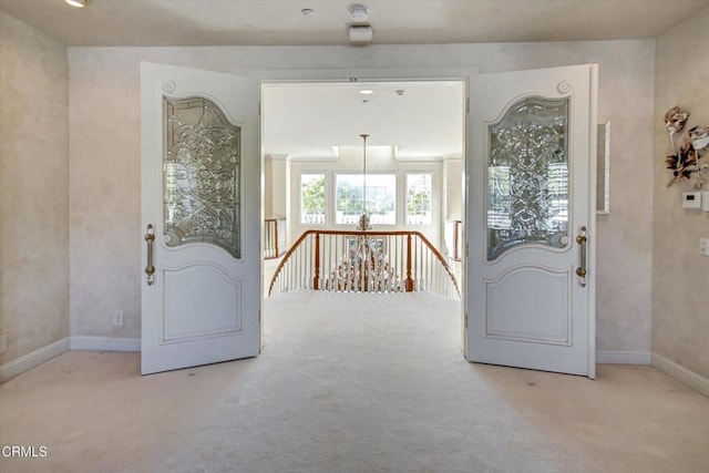 carpeted foyer featuring an inviting chandelier