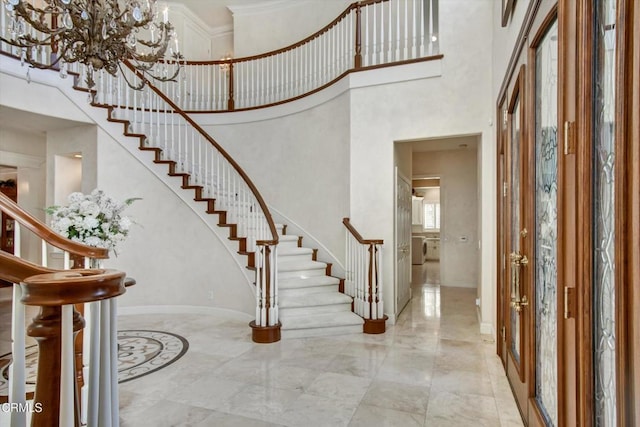 foyer entrance featuring a chandelier, a towering ceiling, and crown molding