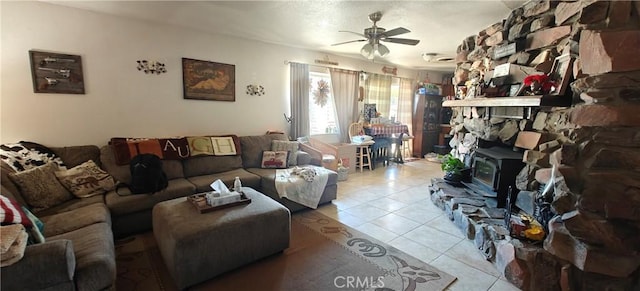 tiled living room with a wood stove and ceiling fan