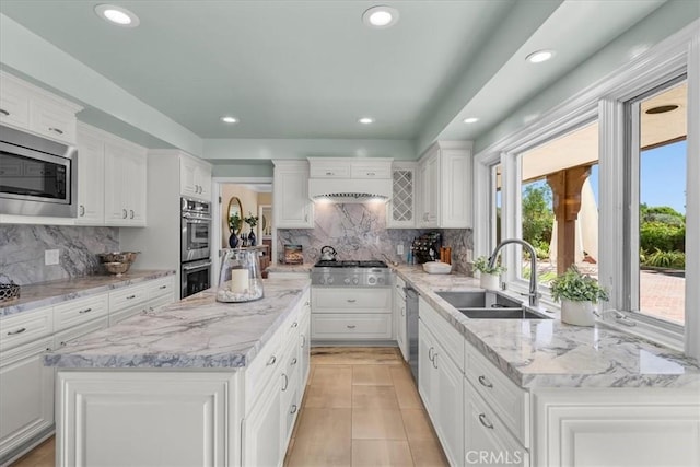 kitchen with white cabinetry, sink, a center island, tasteful backsplash, and appliances with stainless steel finishes