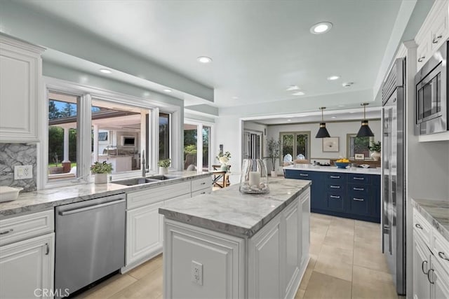 kitchen with built in appliances, a center island, white cabinetry, and sink