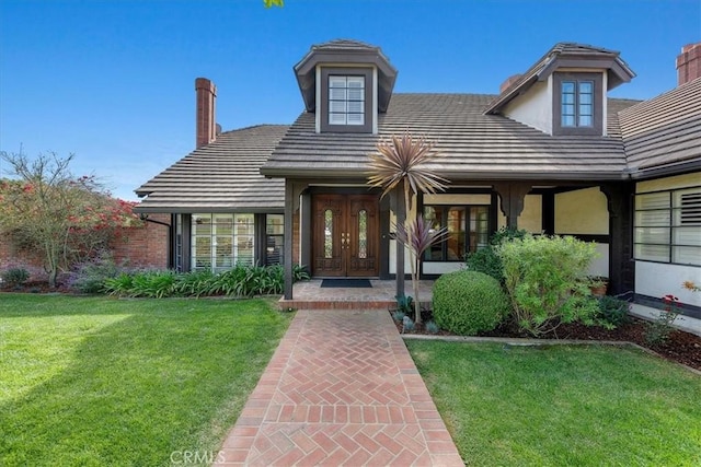 view of exterior entry with a yard and french doors