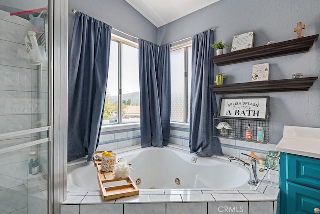 bathroom featuring lofted ceiling, a wealth of natural light, shower with separate bathtub, and vanity