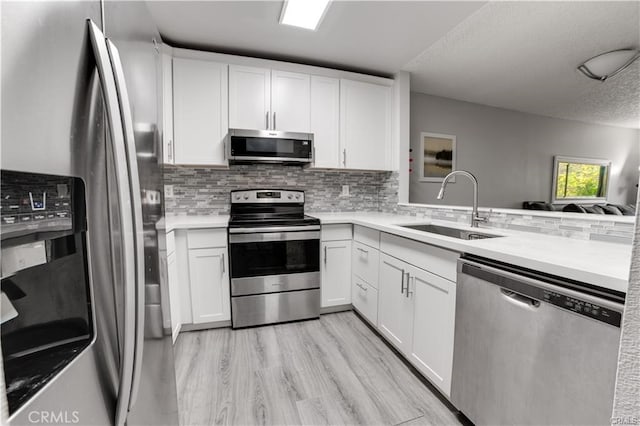 kitchen with white cabinets, a textured ceiling, light wood-type flooring, sink, and stainless steel appliances