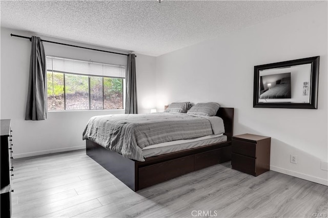 bedroom featuring a textured ceiling and light hardwood / wood-style flooring