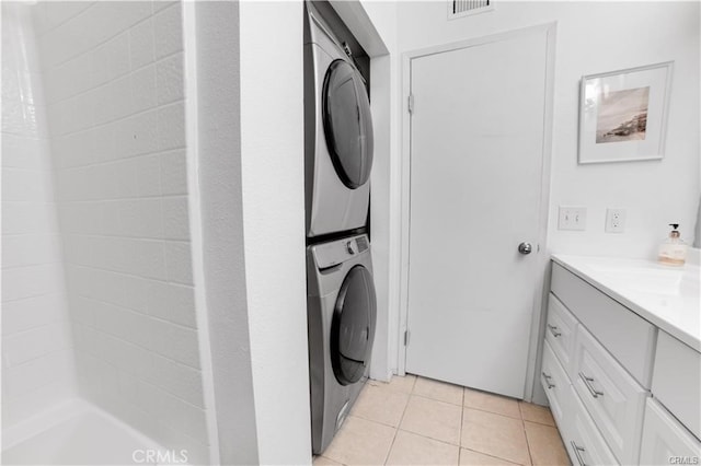 laundry room with stacked washer / dryer and light tile patterned flooring