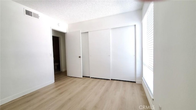 unfurnished bedroom with a closet, light hardwood / wood-style floors, and a textured ceiling