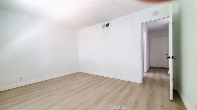 unfurnished room featuring a textured ceiling and light wood-type flooring