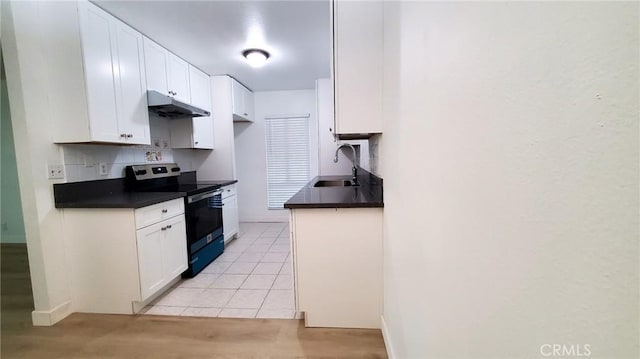 kitchen with tasteful backsplash, sink, light tile patterned floors, electric range, and white cabinets