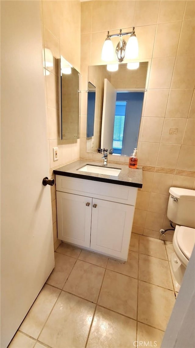 bathroom with tile patterned flooring, vanity, toilet, and tile walls