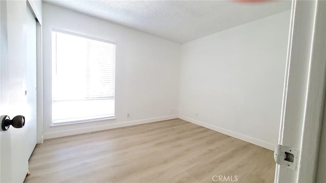 empty room with light hardwood / wood-style flooring and a textured ceiling