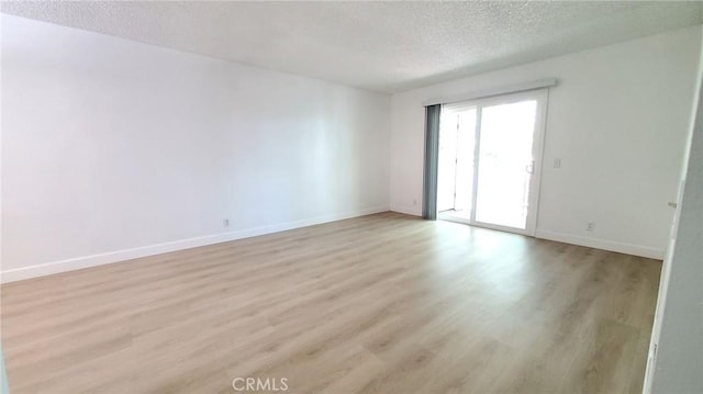 spare room featuring a textured ceiling and light hardwood / wood-style flooring