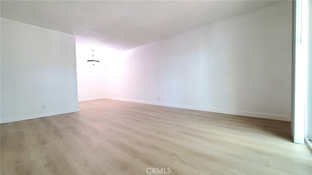 unfurnished room featuring a textured ceiling and light hardwood / wood-style flooring