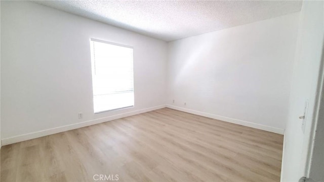 unfurnished room featuring light wood-type flooring and a textured ceiling