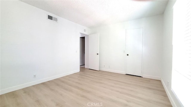 spare room with a textured ceiling and light hardwood / wood-style flooring