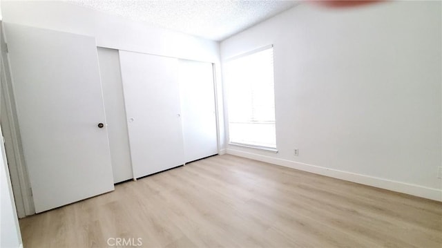 unfurnished bedroom featuring a closet, light hardwood / wood-style floors, and a textured ceiling